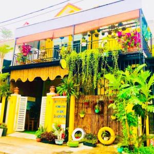 会安An Bang Sea Adventure Homestay Hoi An的一座黄色的建筑,前面有植物