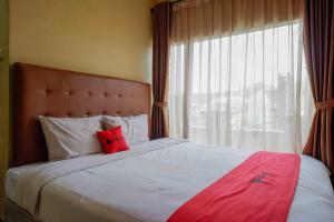 SoloRedDoorz near Rumah Sakit Ortopedi Dr Soeharso的一间卧室配有一张带红色枕头的大床
