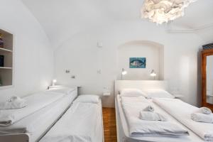 卢布尔雅那ROG Apartment with Furnished Courtyard的配有白色墙壁和吊灯的客房内的三张床