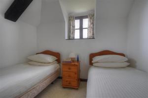 MusburyRose Cottage的一间卧室设有两张床,墙上设有一面镜子
