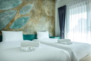 普吉镇Coco Paradiso Phuket SHA的两张位于酒店客房的床铺,配有壁画