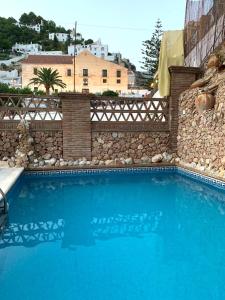 弗里希利亚纳弗里希利亚纳别墅酒店的一座大型蓝色游泳池,毗邻石墙