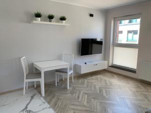 格但斯克Olin Apartament B - Gdańsk Angielska Grobla的客厅配有白色桌子和电视