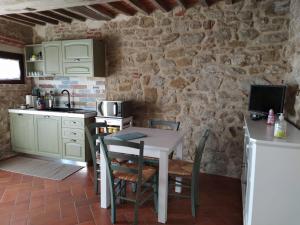 特拉西梅诺湖畔托罗Agriturismo L'Accolta的厨房配有桌椅和石墙