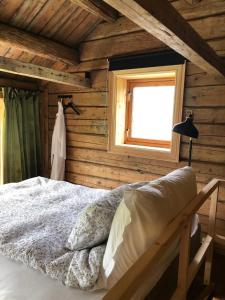 斯彻达尔Stokke Gård Burglamping的一间卧室设有木墙和一张带窗户的床