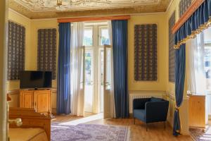 卡罗维发利哈鲁恩酒店的一间卧室配有蓝色窗帘、椅子和电视