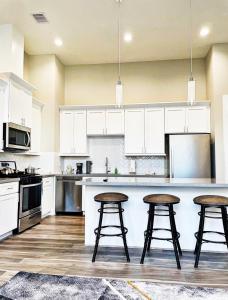 休斯顿Modern Style Relaxation in Houston, Texas的厨房配有白色橱柜和3个酒吧凳