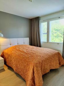 罗瓦涅米Lovely cityhome的一间卧室配有一张带橙色棉被的床和窗户