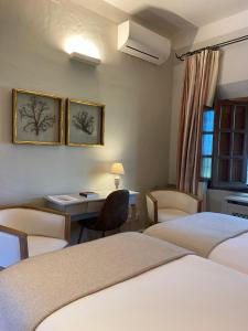 ValdecaballerosHotel Rural Las Tejuelas的酒店客房带两张床和一张桌子以及椅子。