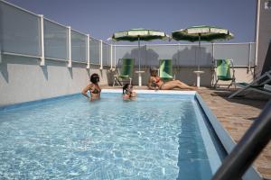 佩萨罗Amadei Hotel Figaro & Apartments的三个女孩坐在游泳池里