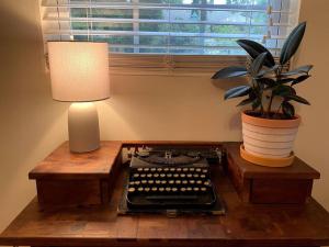 欧佩莱卡The Greenhouse Cozy Cottage- Walk to Downtown!的一张桌子,上面有台灯,旧的打字机和植物