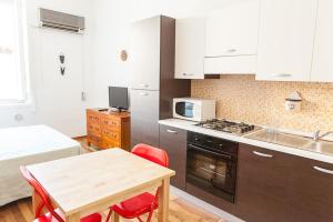 卡利亚里S Efisio in Cagliari Centre Q4825的厨房配有白色橱柜和红色椅子的桌子