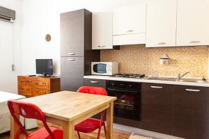 卡利亚里S Efisio in Cagliari Centre Q4825的厨房配有木桌和红色椅子