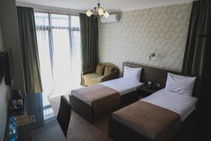 巴统Old Garden Hotel Batumi的酒店客房,配有两张床和椅子