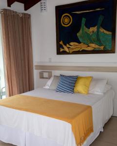 佩尼亚Hotel Maricá的卧室内的一张床铺,墙上有绘画作品