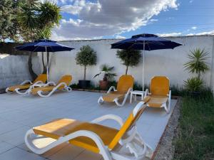 卡萨尔德卡塞雷斯Quinta La Encarnación的庭院里摆放着一组椅子和遮阳伞