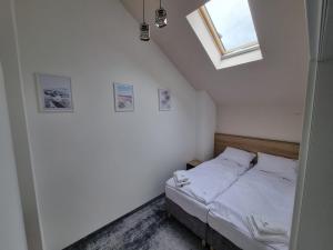 尼彻兹Domki Gold-Time Niechorze的一间卧室配有一张带白色床单的床和一扇窗户。