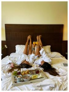 马札冈阿尔拜达自然酒店的两个女人躺在床上,放着一盘食物