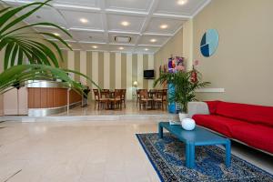 佩萨罗Amadei Hotel Promenade的客厅配有红色的沙发和桌子