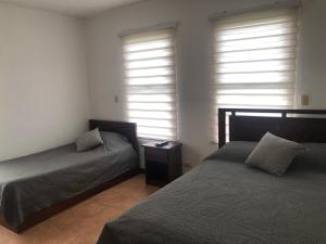 利比里亚Apartamento Chorotega的一间卧室设有两张床和两个窗户。