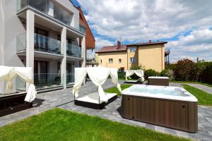 尤尼埃Apartamenty Prestige Mielno-Uniescie的一座带热水浴缸和椅子的庭院以及一座建筑