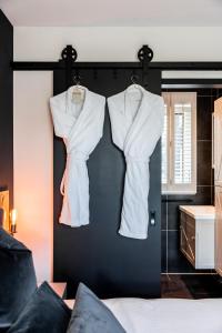ReeuwijkGîte81的两件白色衬衫挂在卧室的黑色墙上