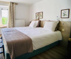 杜柏B&B l'Aigrin的卧室配有一张带白色床单的大床和窗户。