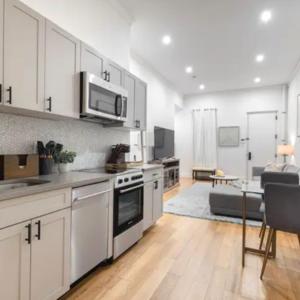 纽约Modern Holiday Apartment with Strategic Location in New York的一间带白色橱柜的厨房和一间客厅