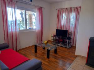布拉托Apartman Luka的客厅配有桌子、电视和红色窗帘