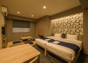 东京KOKO HOTEL Residence Asakusa Kappabashi的酒店客房设有两张床、一张桌子和一张桌子。