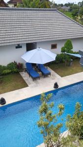 罗威那卡迪卡别墅酒店的游泳池旁的遮阳伞和椅子