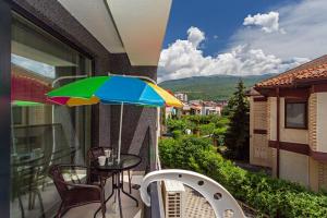 奥赫里德Gric Apartments的阳台配有桌子和多彩的雨伞。