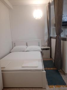 洛帕Apartmani Ana-Lora的一张白色的床,位于一个小房间里,配有桌子