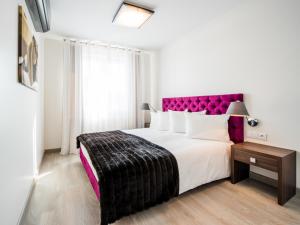 比亚韦斯托克中心高级套房公寓的一间卧室配有一张大床和紫色床头板
