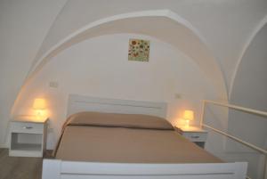 圣凯撒利亚温泉Monolocali a Palazzo Rizzelli的一间卧室配有一张带两张桌子和两盏灯的床。