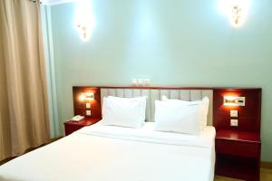 雅温得Hôtel Sindz Palace的一间卧室配有带白色床单和枕头的床。