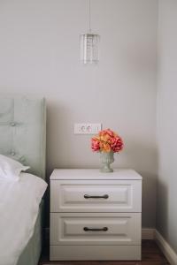 奥拉迪亚GOLD Suites的白色的床头柜,上面有花瓶