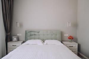 奥拉迪亚GOLD Suites的一间卧室配有一张带2个床头柜的大型白色床