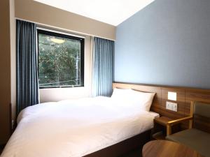 御殿场市Dormy Inn Express Fujisan Gotemba的卧室配有白色的床和窗户。