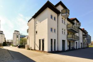 科特布斯Spreewald-Apartment, 75qm, 2 Schlafzimmer, Tiefgarage, Balkon, Netflix, Waschtrockner的一条白色的街道上,有黑色屋顶