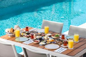 阿拉恰特Muse Alaçatı的一张桌子,旁边是游泳池,提供早餐食品和饮料