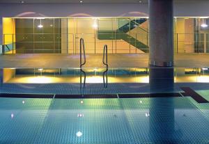 杜塞尔多夫Hotel Kö59 Düsseldorf - Member of Hommage Luxury Hotels Collection的大楼内一个带两把椅子的游泳池