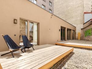 维也纳numa l Wood Rooms & Apartments的两把椅子坐在大楼前的木甲板上