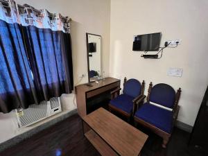 贾姆谢德布尔Hotel Chandra的一间设有两把椅子、一台电视和镜子的房间