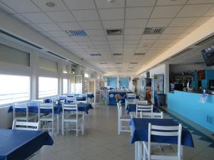 西尔维拉Hotel Apartamento Praia Azul的一间设有蓝色桌子和白色椅子的餐厅
