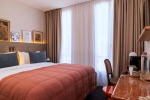 巴黎Hotel Dadou Paris的酒店客房设有床、桌子和窗户。