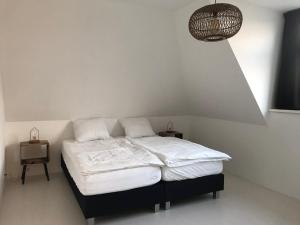 卡兰茨奥赫Dorpsweg 18 nummer 7的一间卧室配有一张带白色床单和一盏灯的床。
