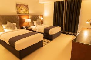 塞拉莱Tulip Inn Majan Hotel的酒店客房设有两张床和窗户。