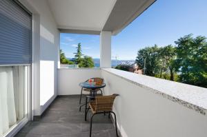 伊齐齐Villa Icici的白色墙壁上的阳台配有桌椅