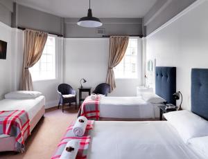 悉尼悉尼大酒店的一间卧室配有两张床和一张桌子及椅子
